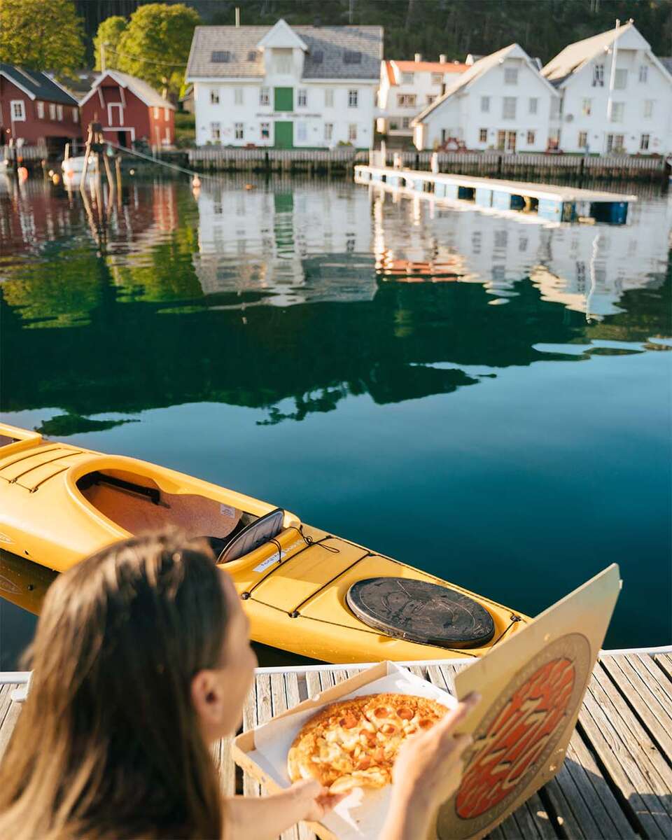 Kvinna äter pizza på brygga