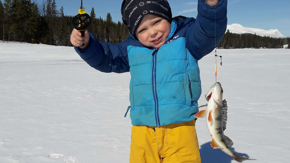 Barn håller upp en fisk 